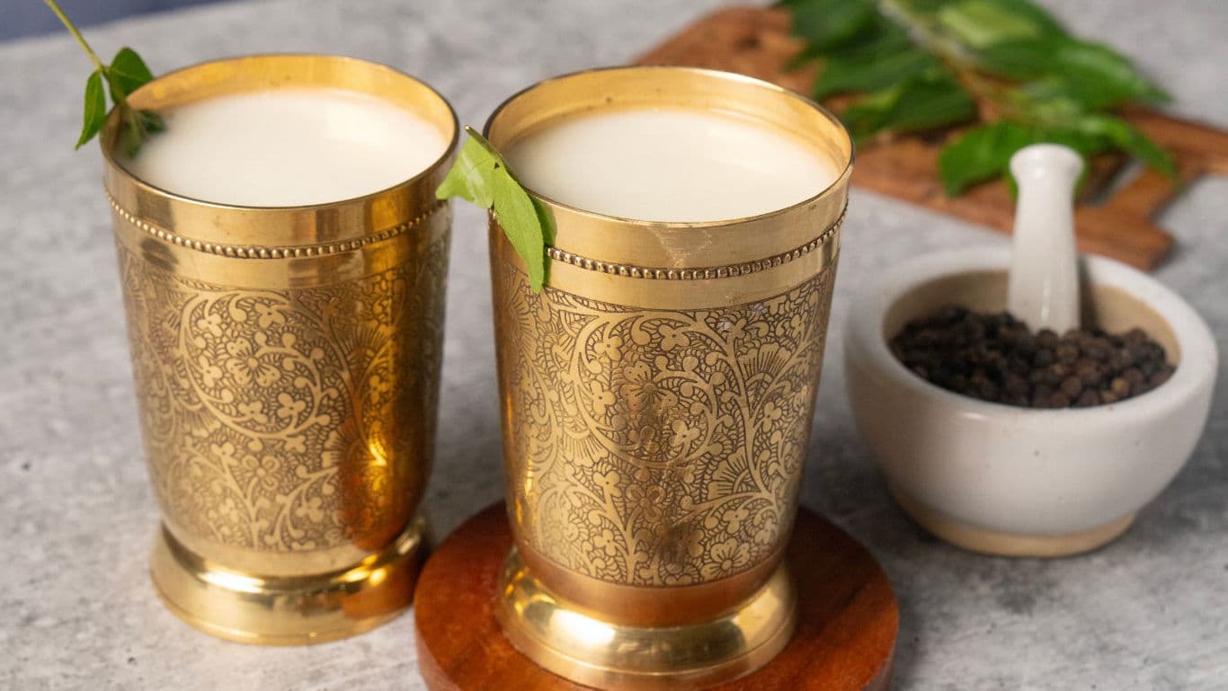Two Brass Tumblers With Traditional Drink and Leaf Garnish