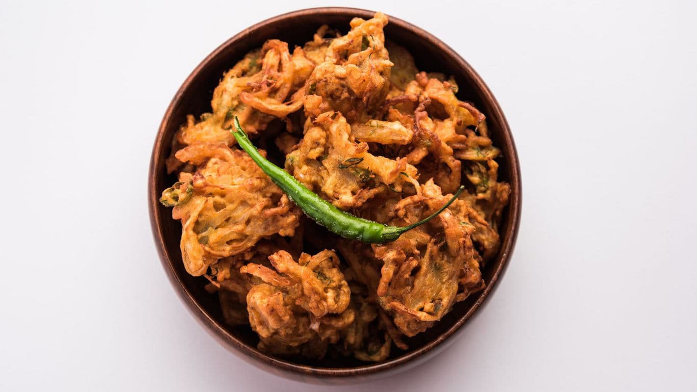 Crispy onion pakora with green chili garnish