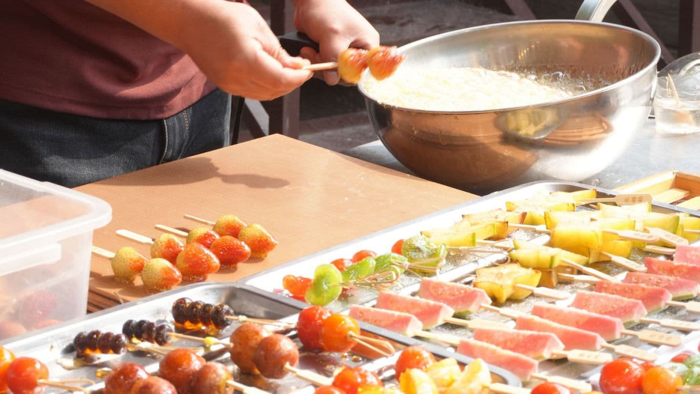 Street vendor preparing colorful fruit skewers