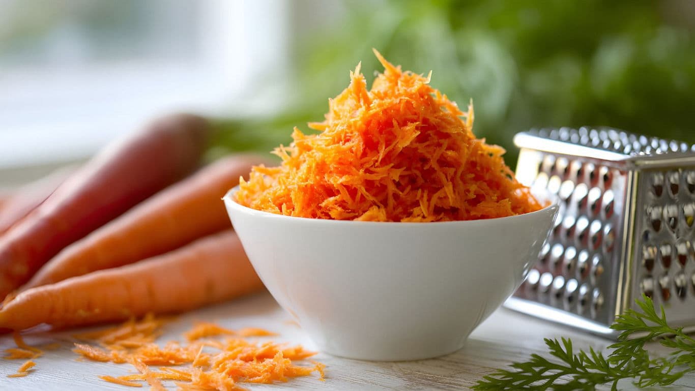 Freshly Grated Carrots in White Bowl on Table