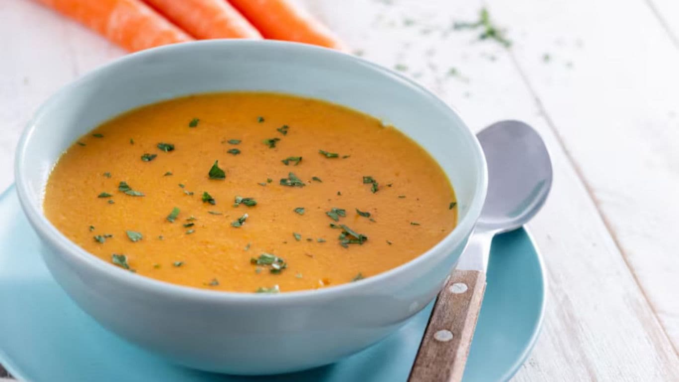 Creamy carrot soup garnished with fresh herbs