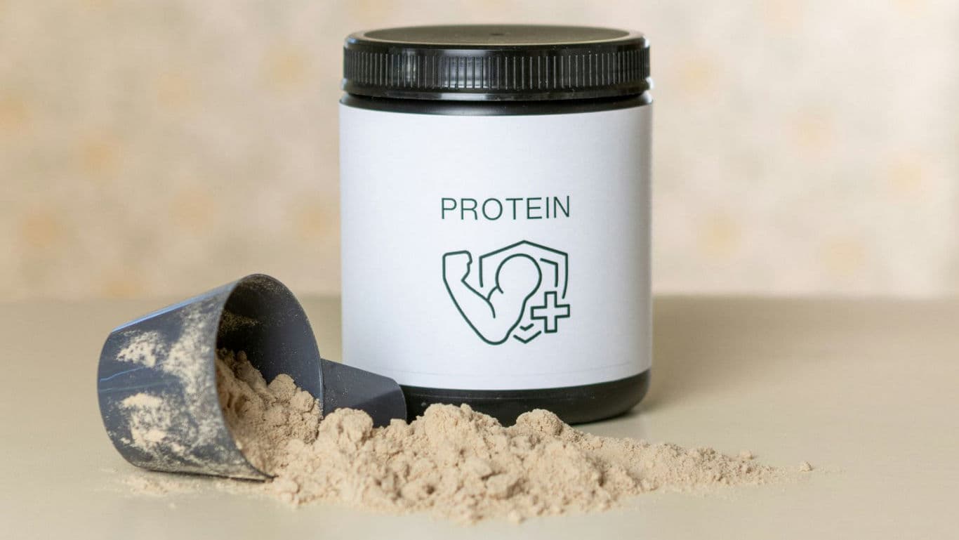 Protein powder container with scoop on table