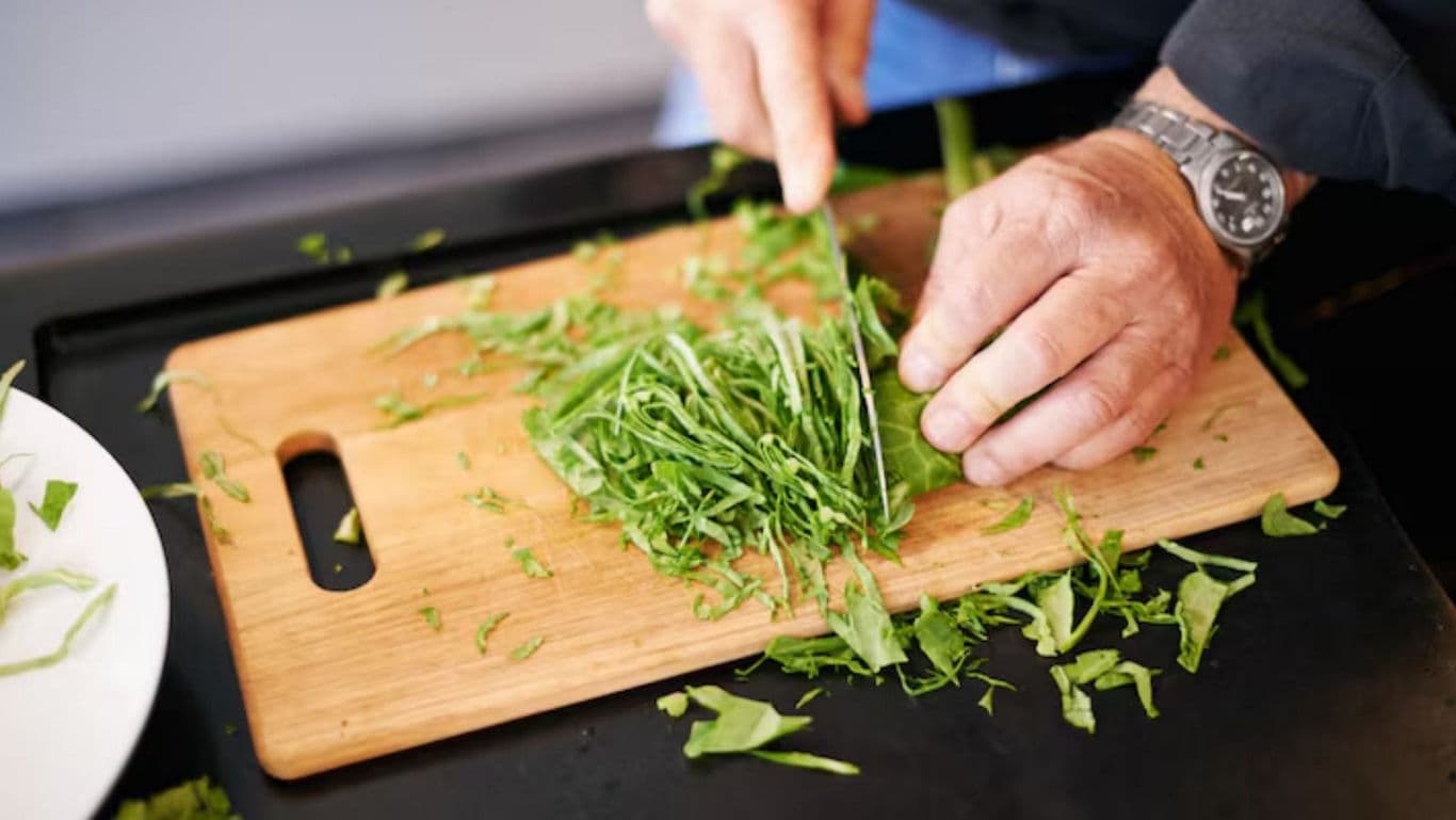 Person chopping fresh green herbs on cutting board