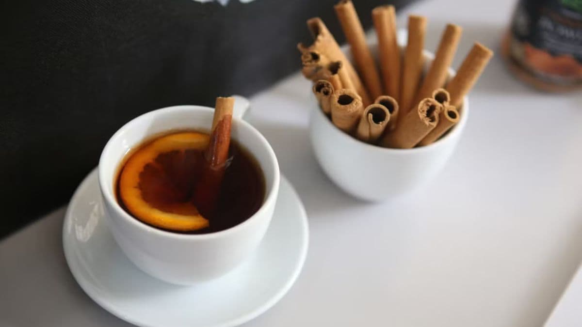 A cup of cinnamon tea with sticks on side