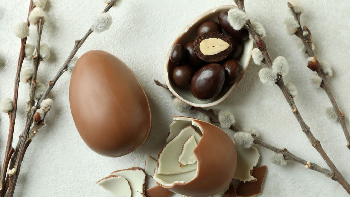 Chocolate Easter eggs with candy on light background
