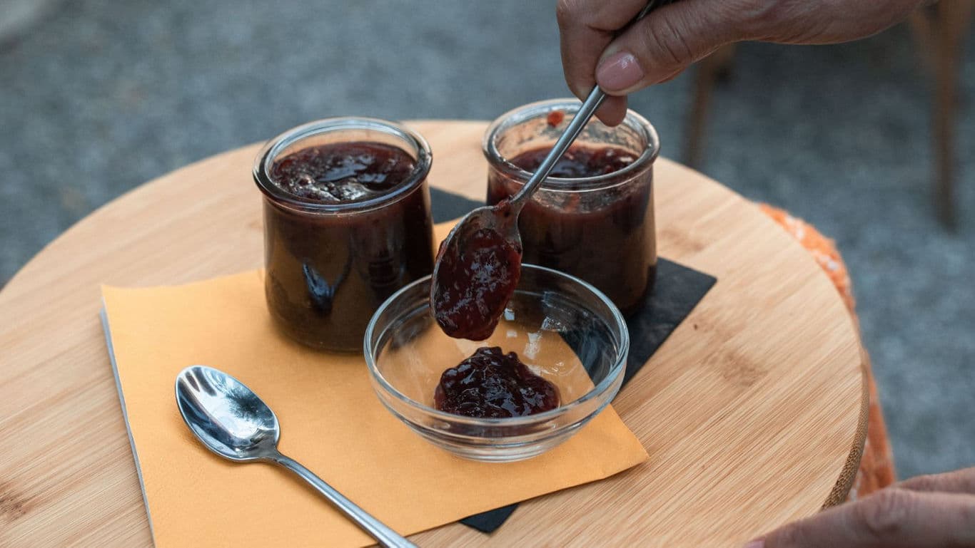Hand serving homemade fruit jam in jars