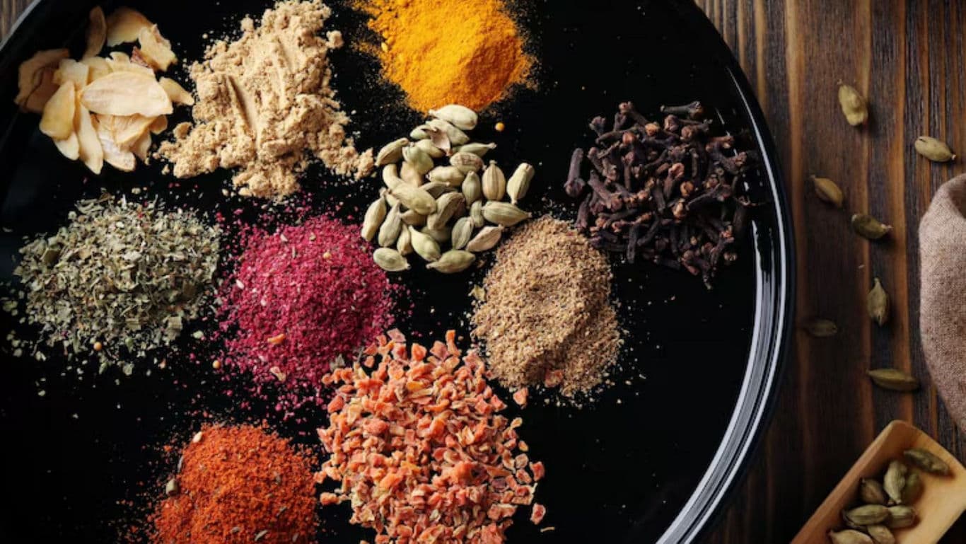 Assorted spices on black plate with cardamom