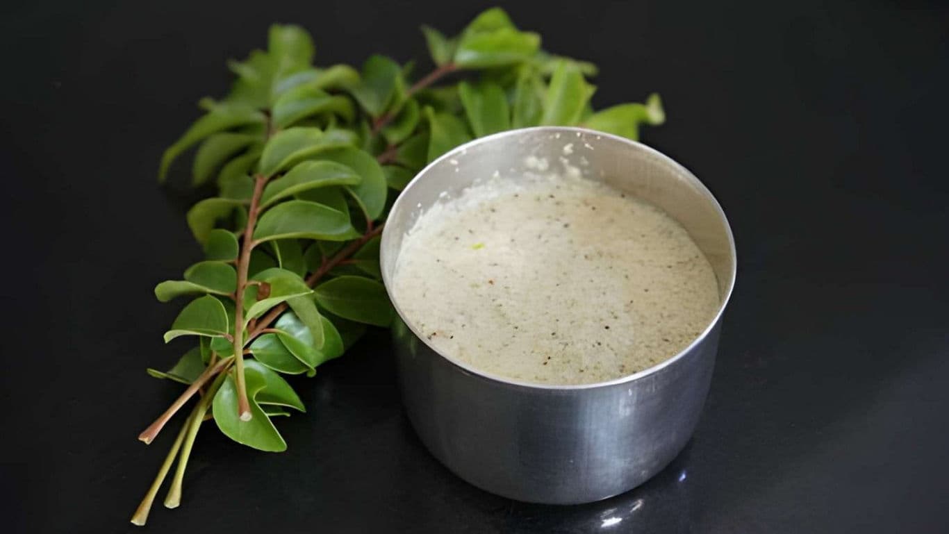 Stainless steel bowl of chutney with fresh curry leaves