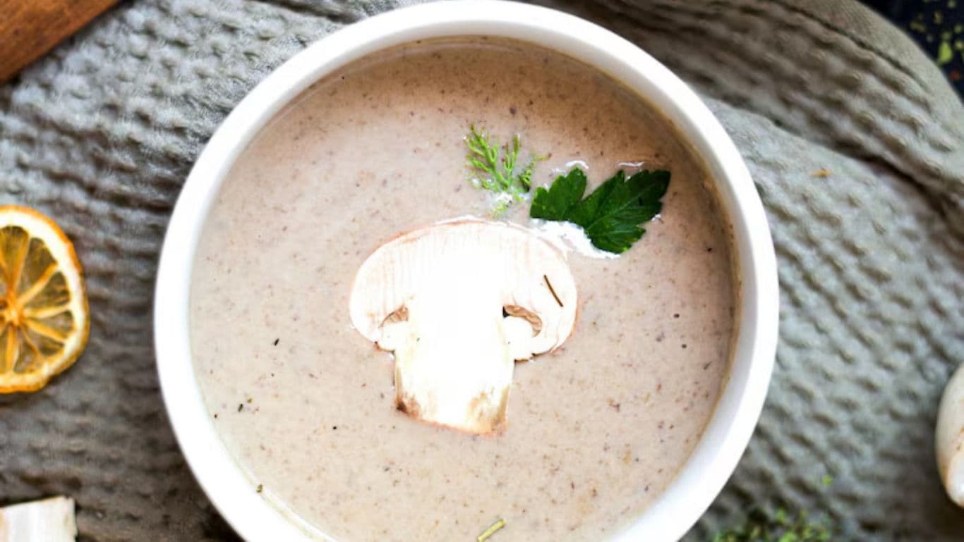 Creamy mushroom soup garnished with parsley leaf