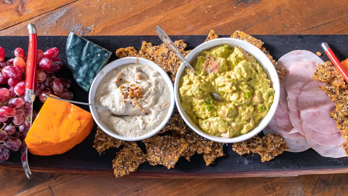 Charcuterie board with dips, cheese, grapes, and ham