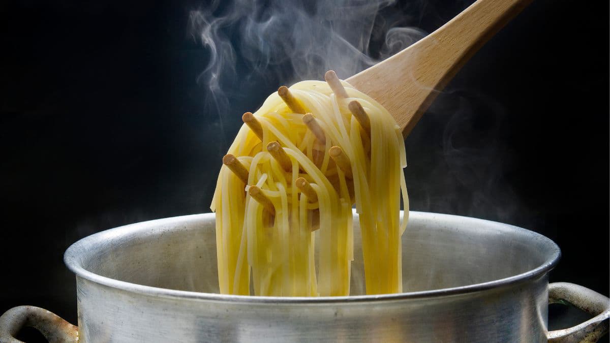 Spoon holding up freshly cooked noodles over a pan