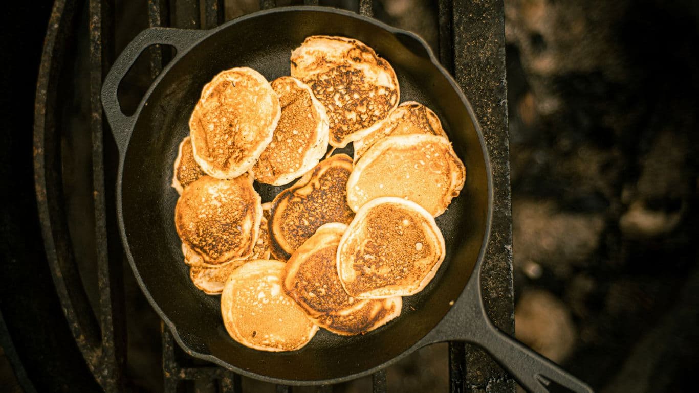 Golden pancakes cooking in cast iron skillet