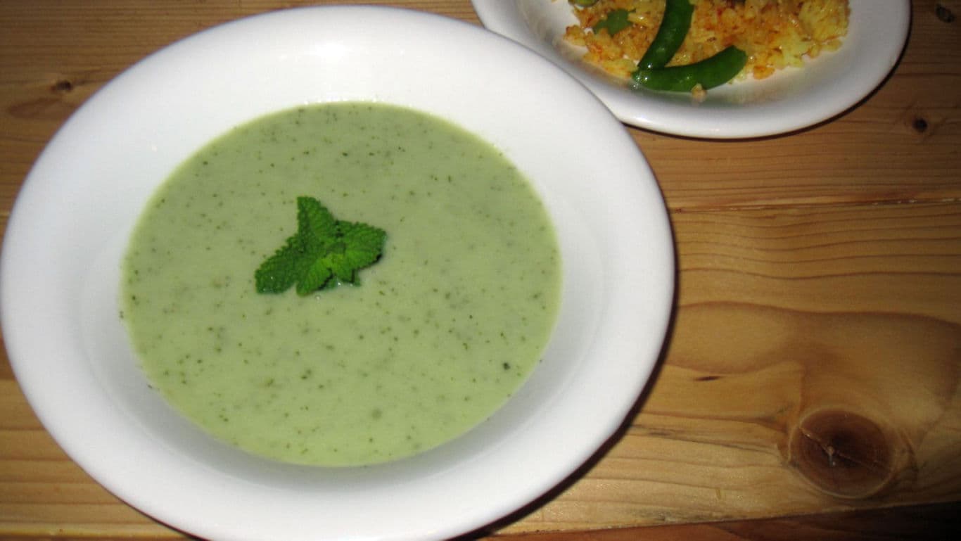 Creamy green soup garnished with mint leaves