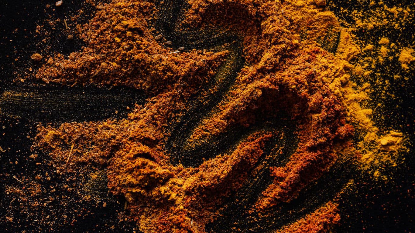 Vibrant turmeric and spice powder on dark surface