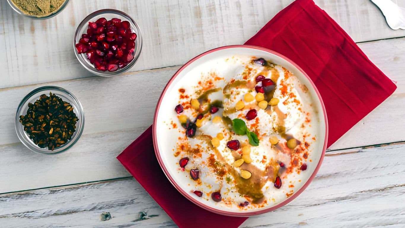 Indian yogurt dish garnished with pomegranate and spices