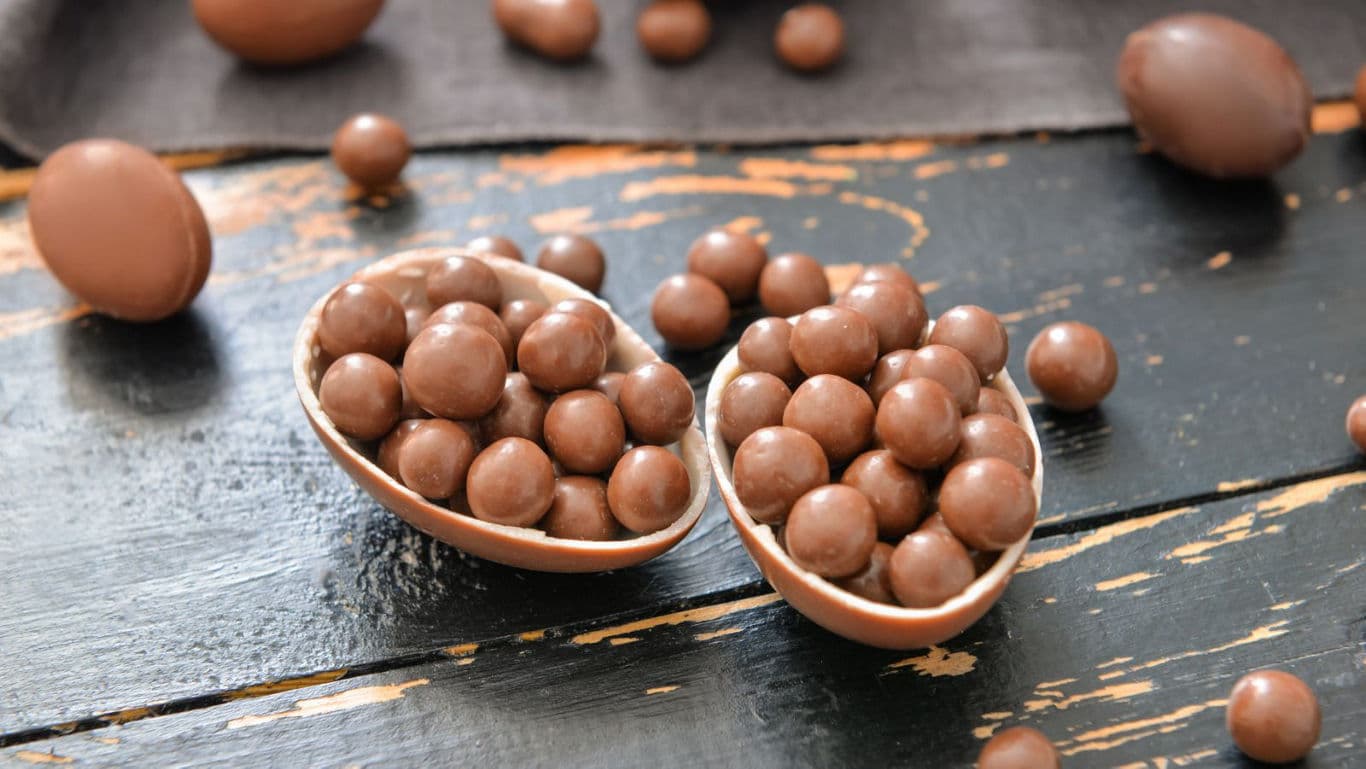 Chocolate egg halves filled with round candies on table