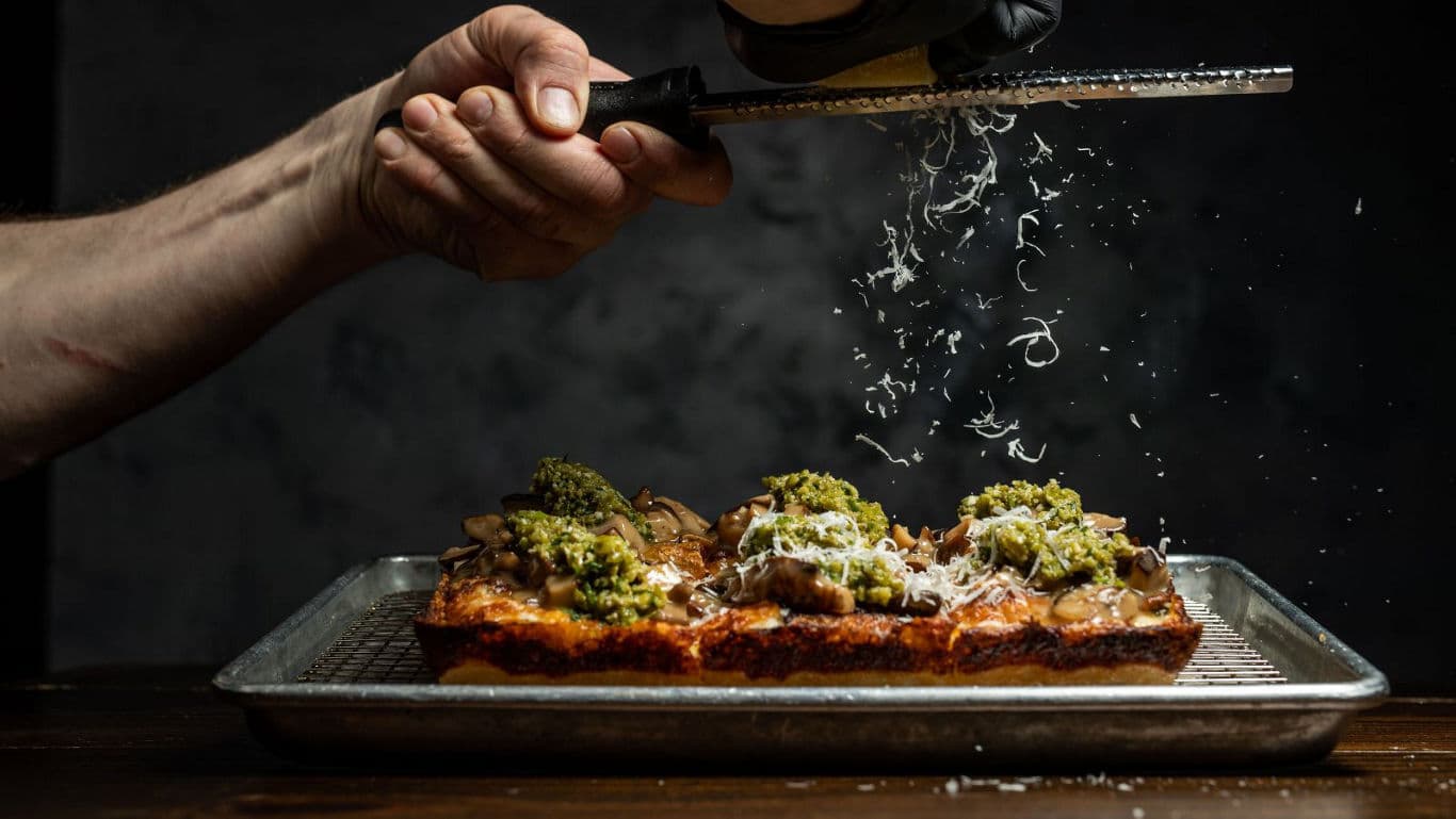 Chef grating cheese over gourmet focaccia