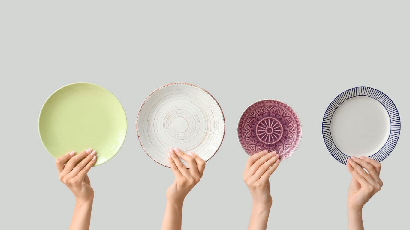 Hands holding assorted decorative ceramic plates