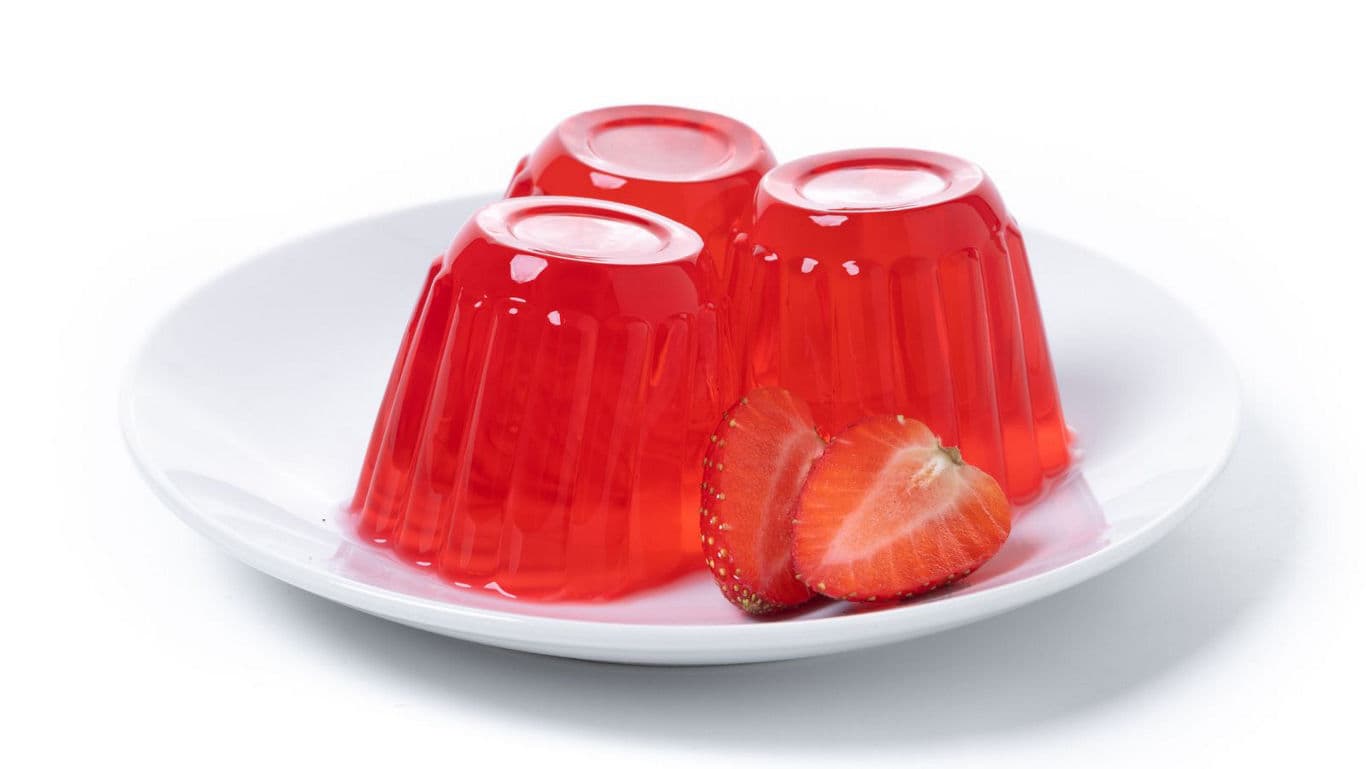 Red gelatin dessert with fresh strawberries on plate
