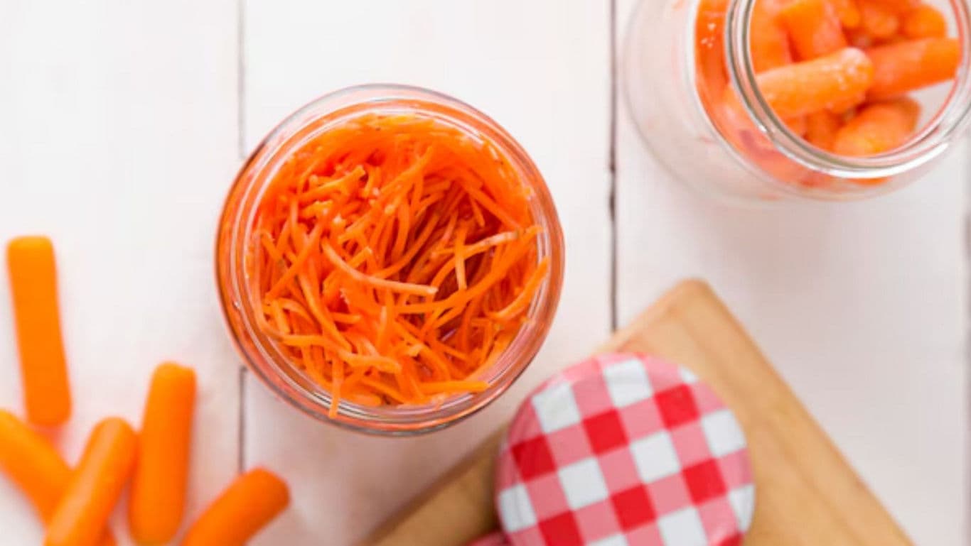 Shredded and Whole Carrots in Glass Jars on Table