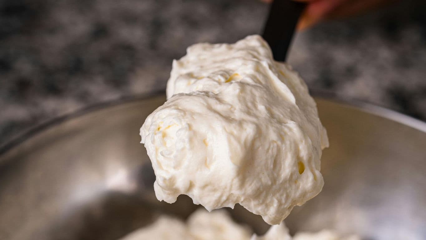 Close-up of whipped cream in metal mixing bowl