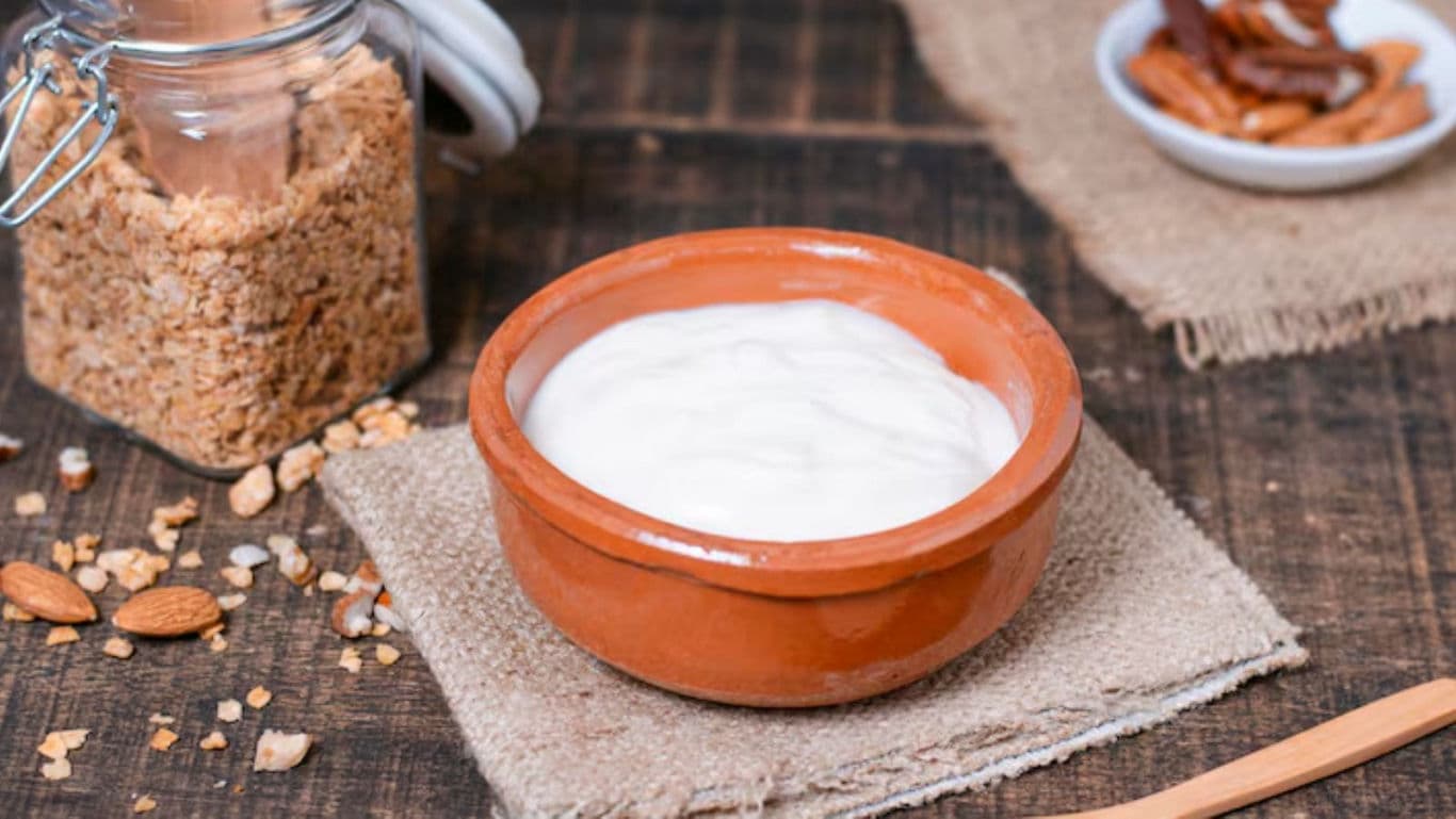 Clay bowl of yogurt with granola and almonds