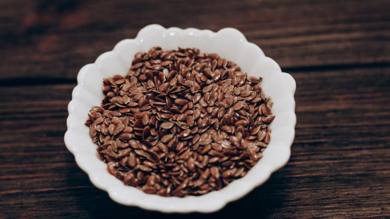 White bowl of flaxseeds on wooden table