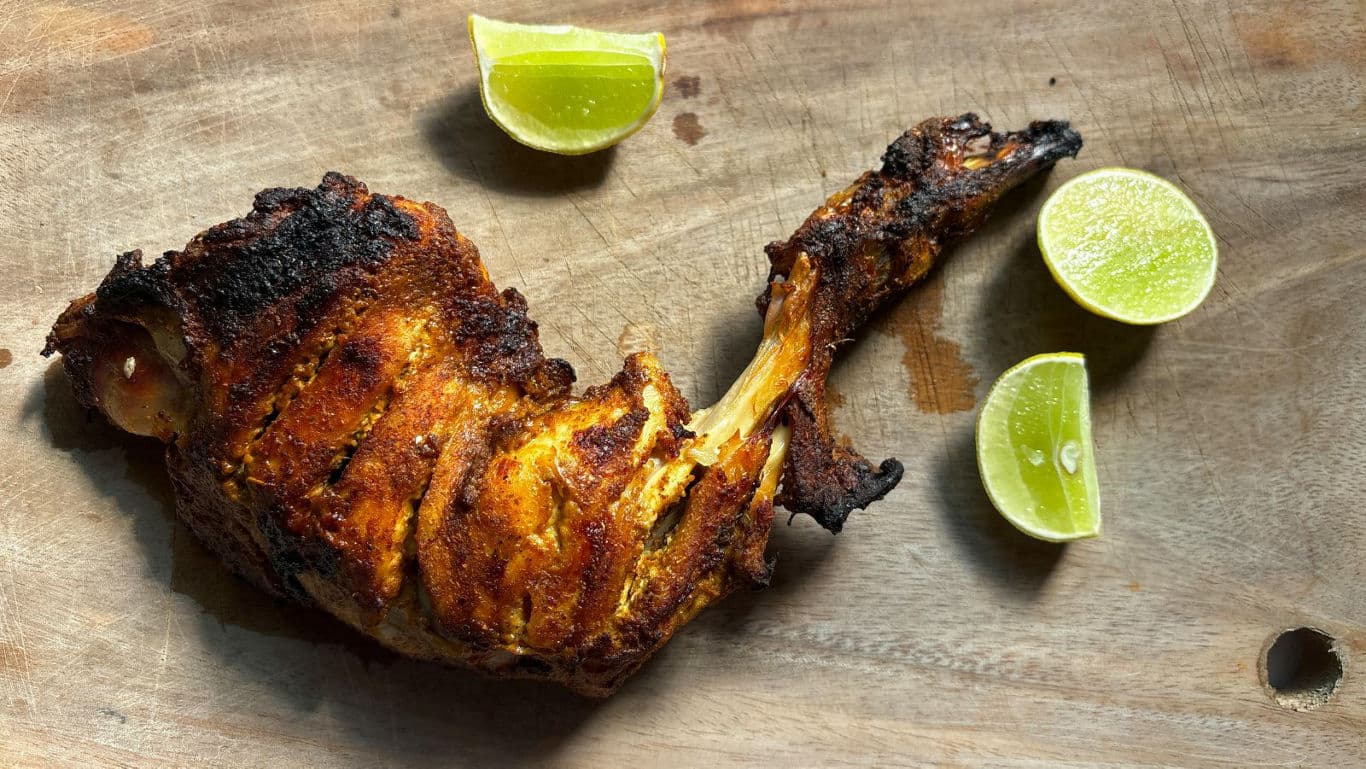 Grilled spiced chicken leg with lime wedges