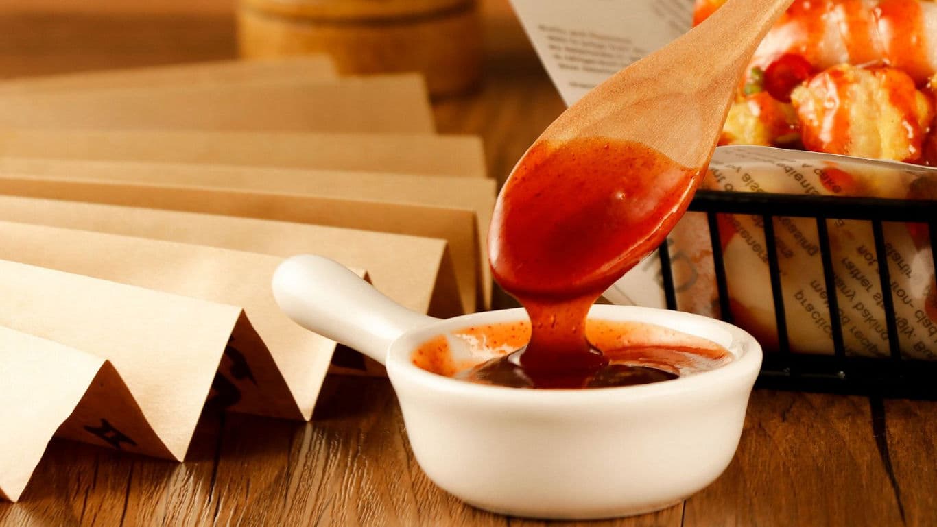 Wooden spoon dipping into red sauce