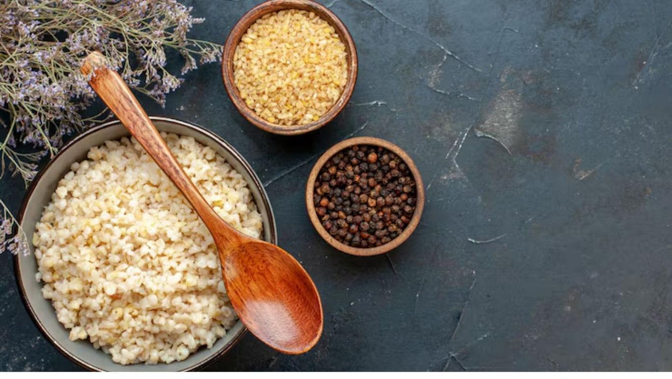 Cooked bulgur with spices and wooden spoon