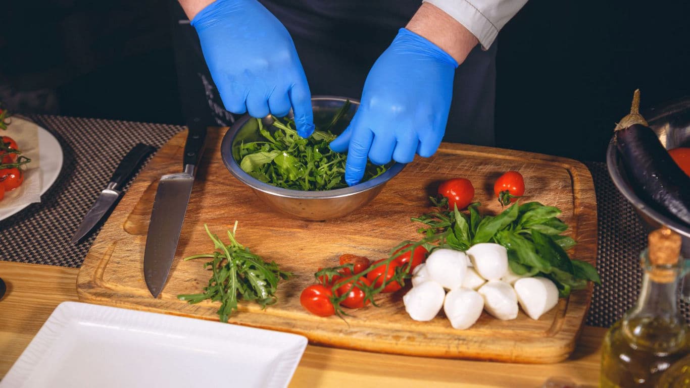 Chef preparing fresh salad ingredients on board