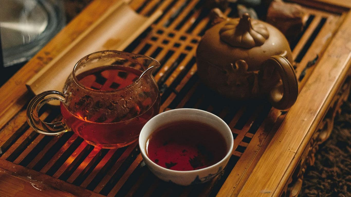 Tea leaves being put inside a teapot.