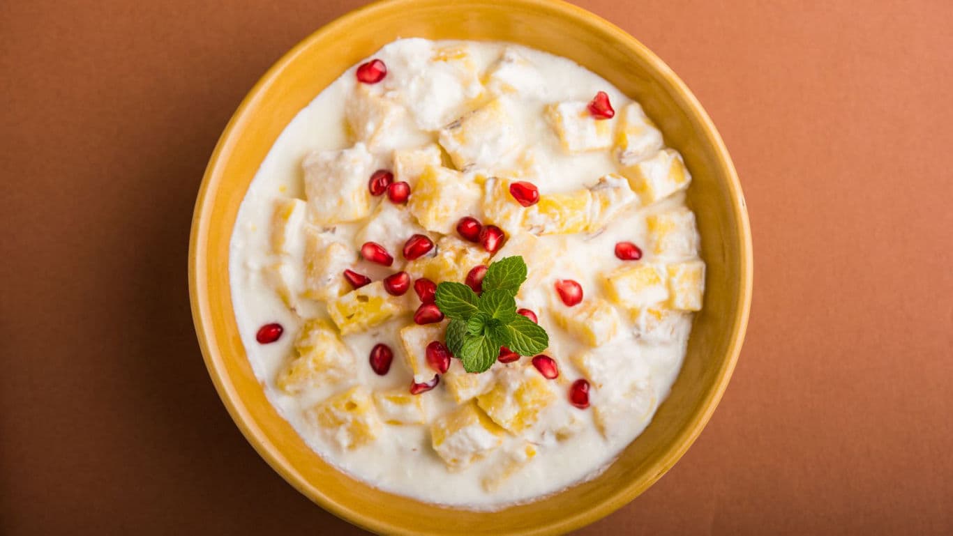 Bowl of fruit raita with pomegranate and mint garnish