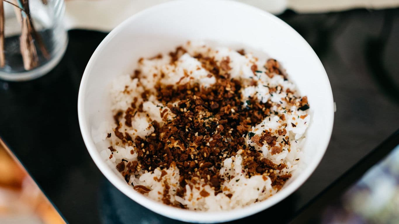 White rice topped with savory seasoning in bowl
