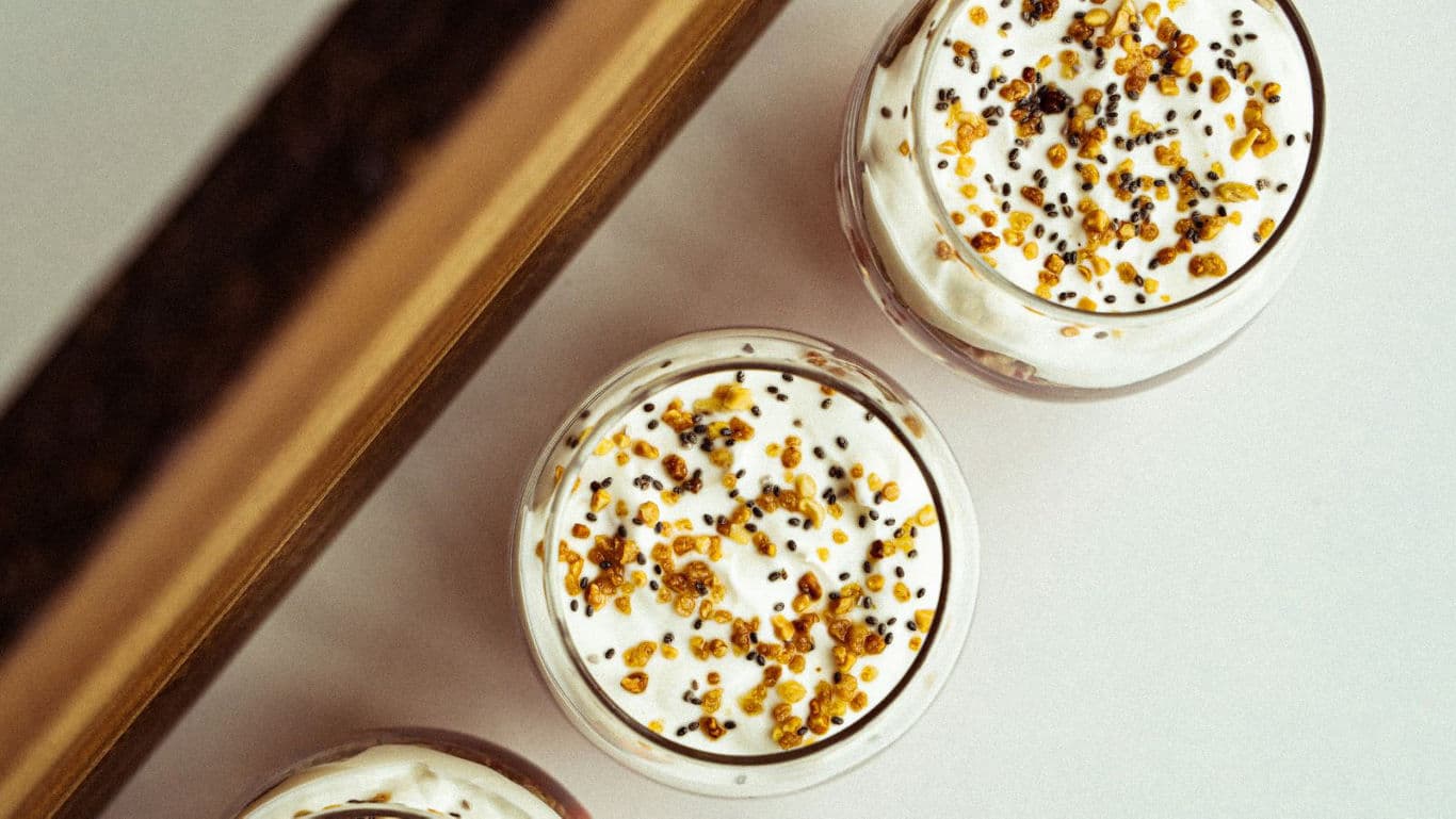 Creamy dessert glasses topped with seeds and honey