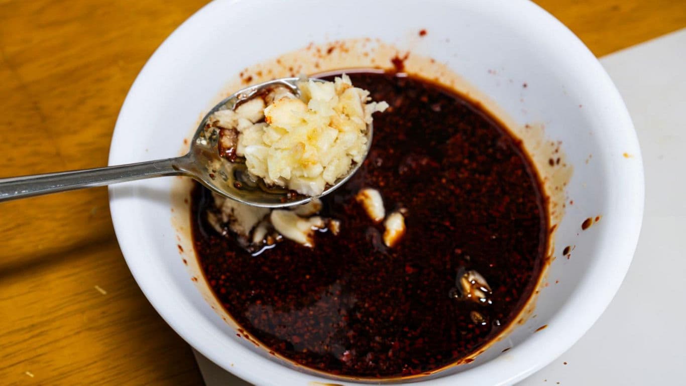 Spoonful of Chopped Garlic Over Spicy Sauce Bowl