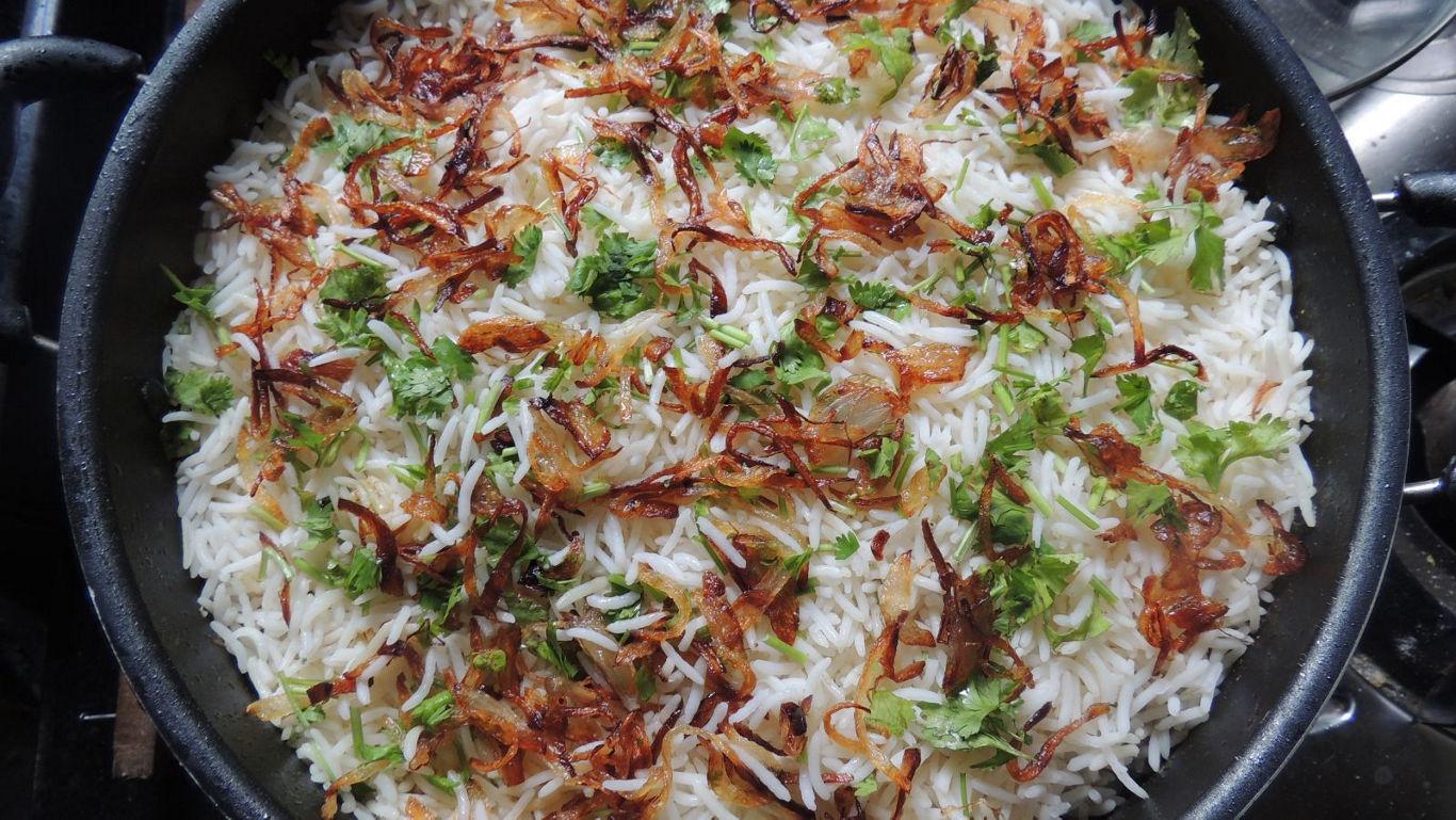 Aromatic Eid biryani served in a clay pot bowl with mint and fried onions on top.