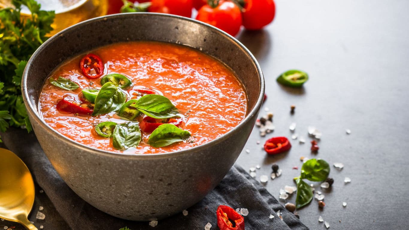 Fresh tomato soup garnished with basil and chili
