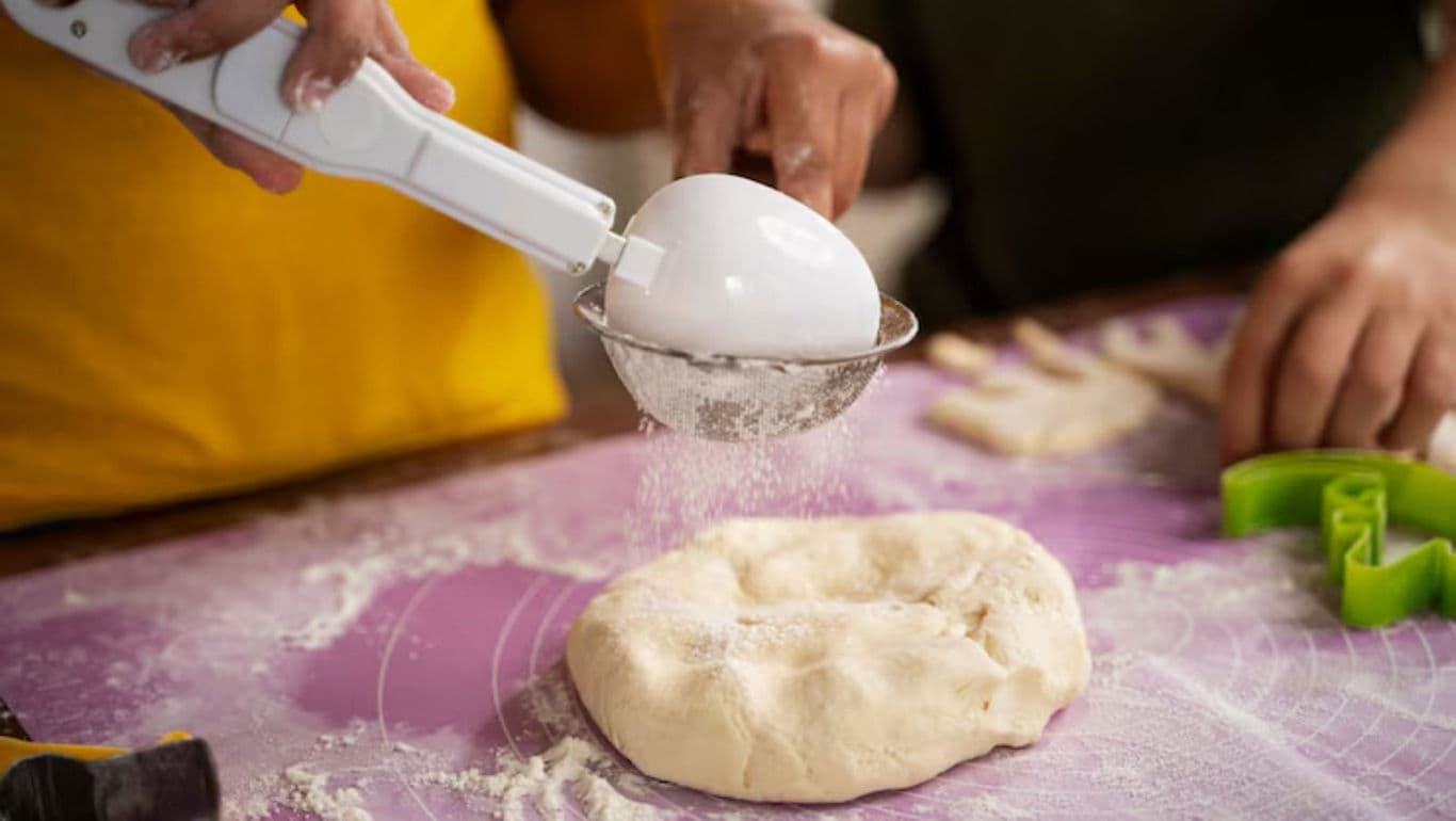 Hands preparing dough with flour sifter