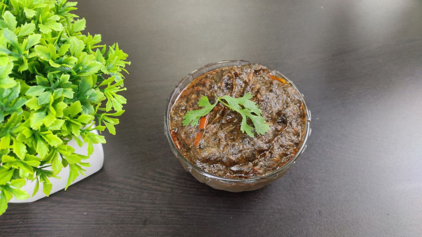 Bowl of dark herb stew on table