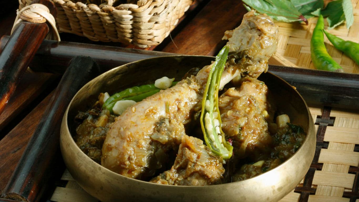 Spicy chicken curry served in brass bowl