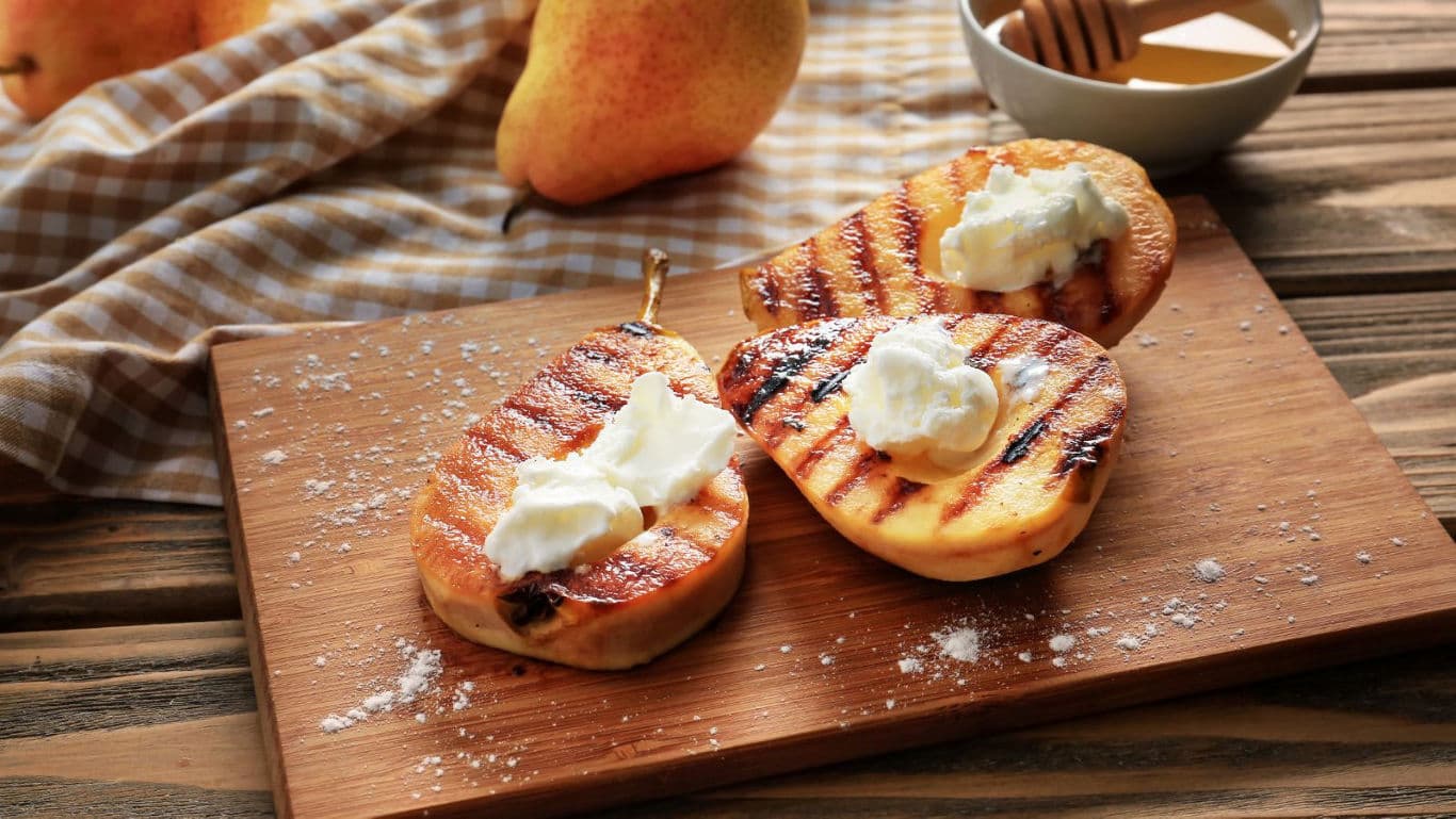 Grilled Pear Halves with Cream on Wooden Board