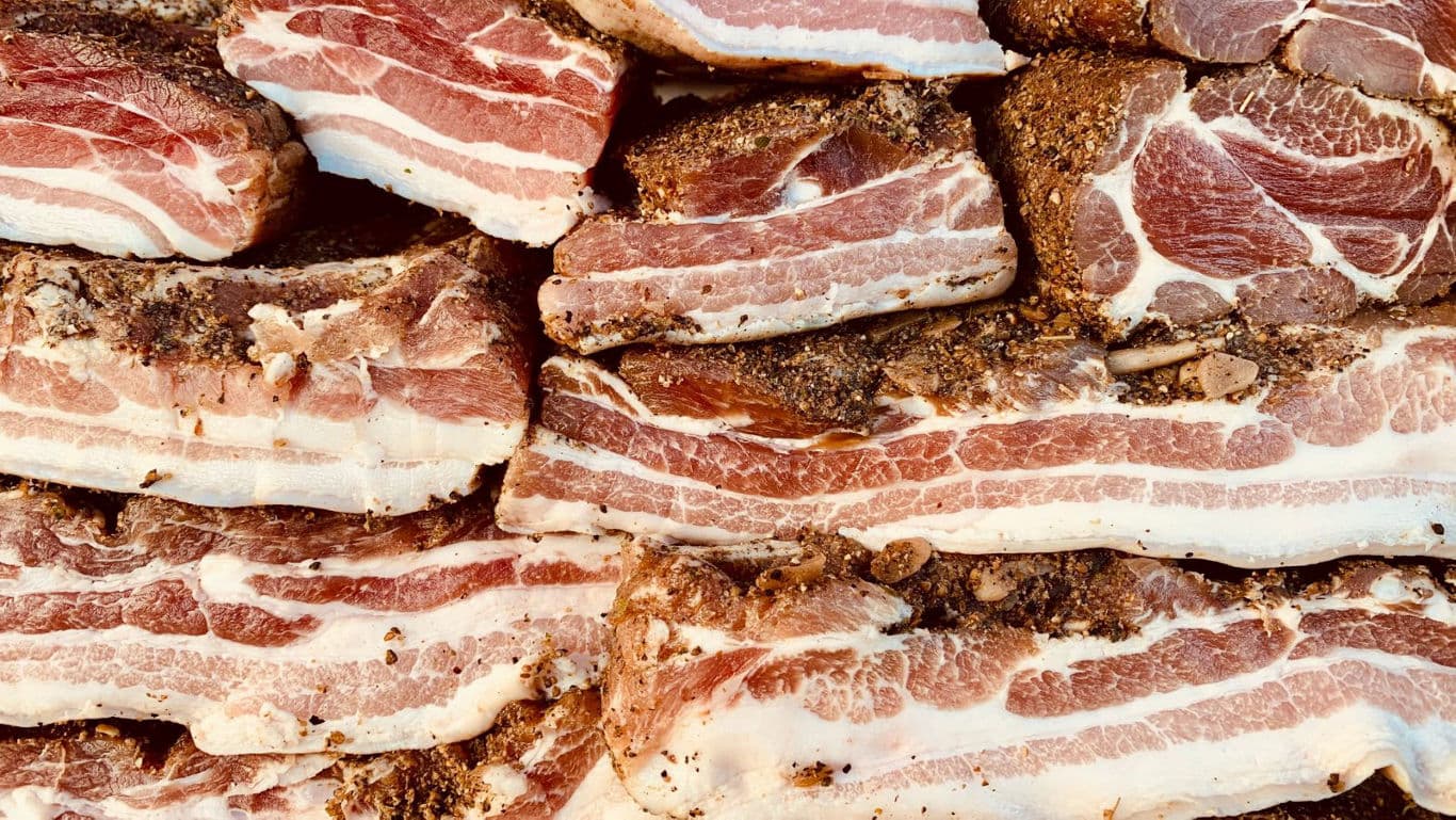 Stacked seasoned bacon slices close up