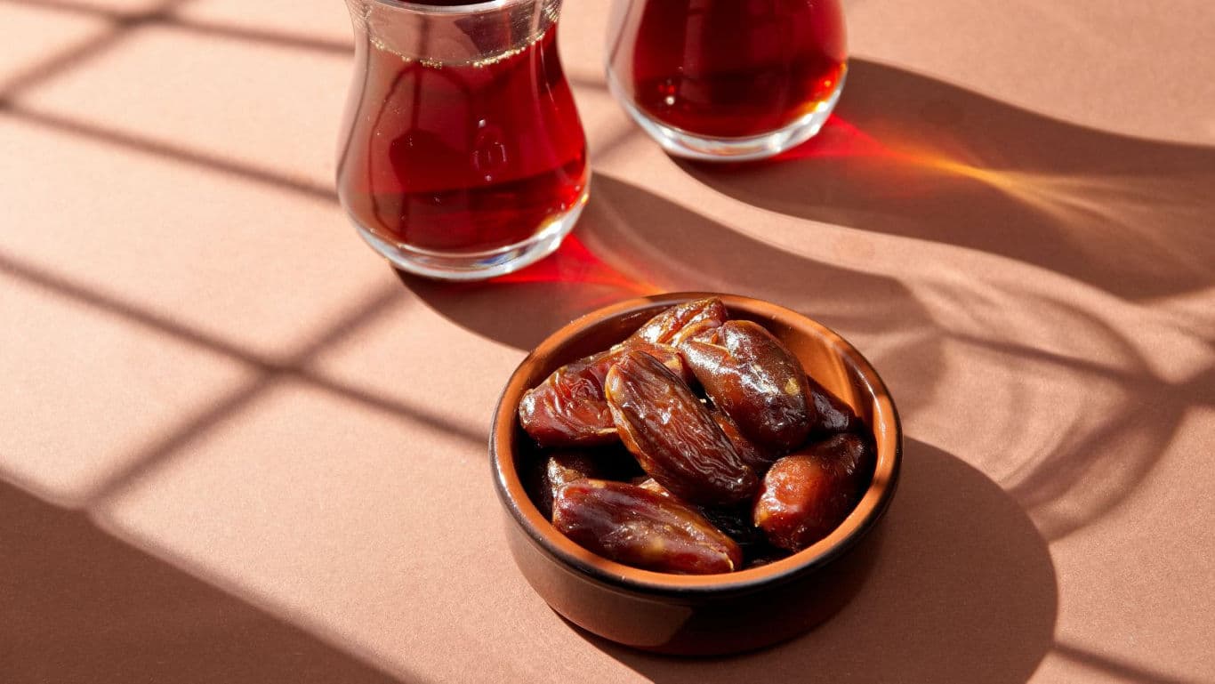 Bowl of dates with tea glasses in sunlight