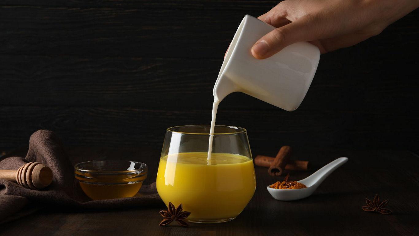 Pouring milk into turmeric drink