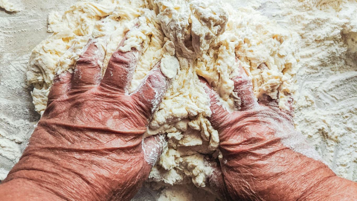 Hands kneading a khapli atta dough.