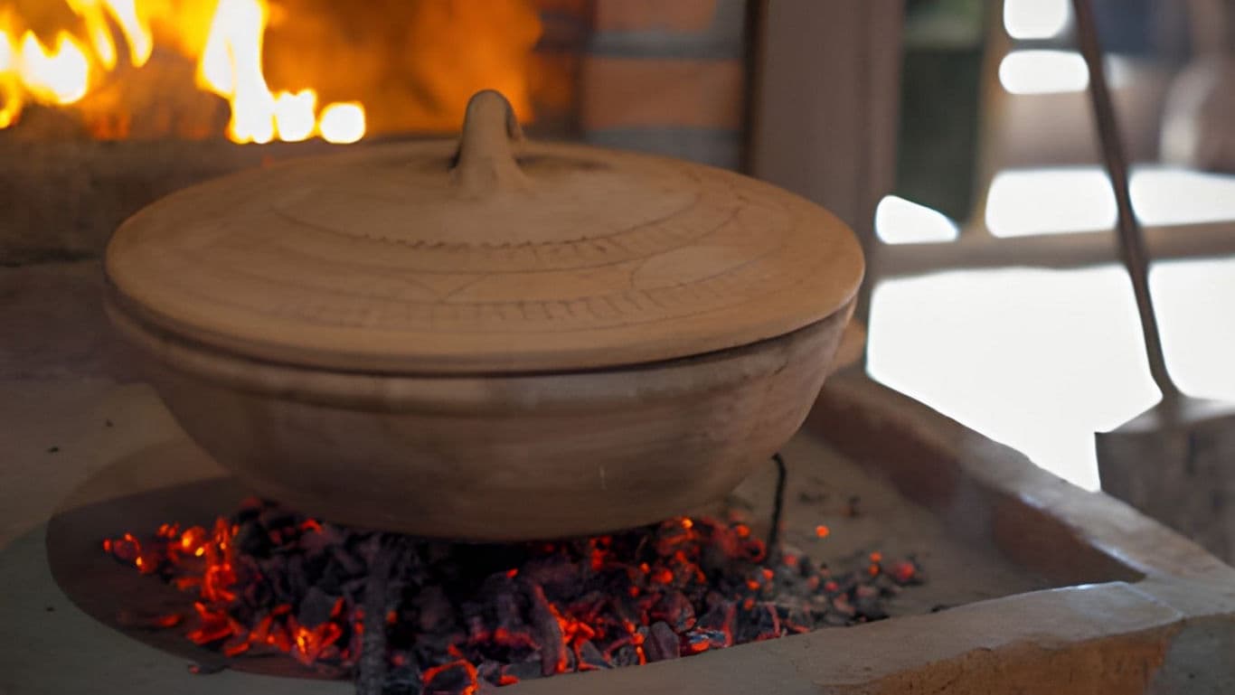 Clay pot cooking over glowing charcoal embers