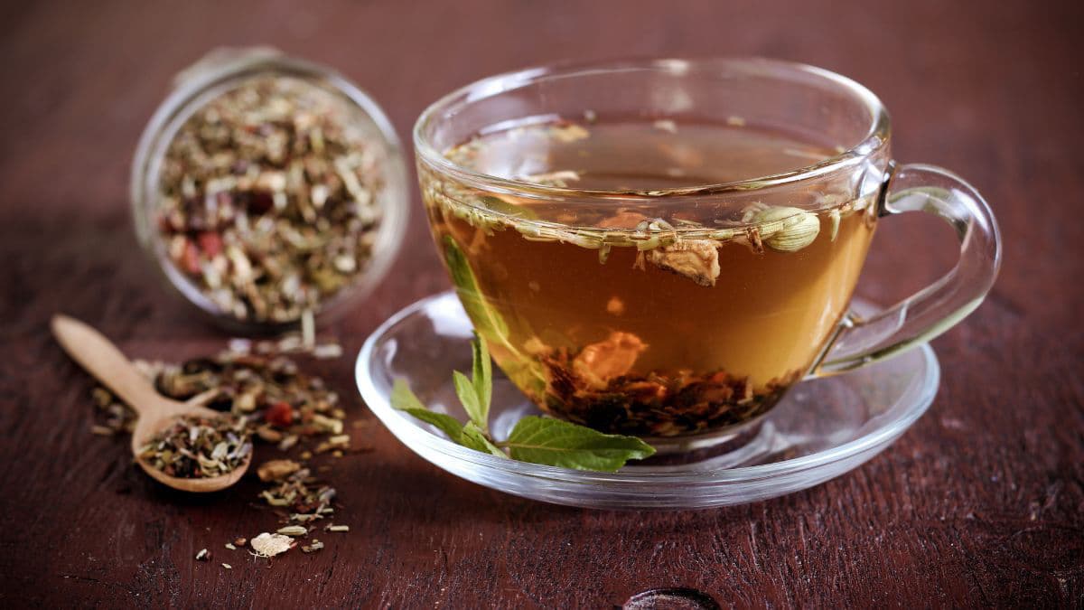 a cup of herbal tea with herbs on the side