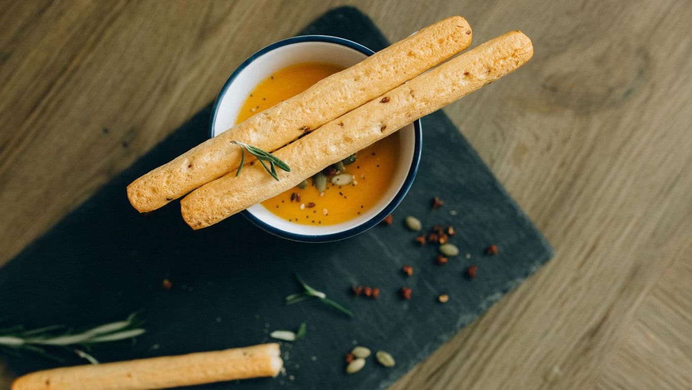 Breadsticks served over creamy pumpkin soup