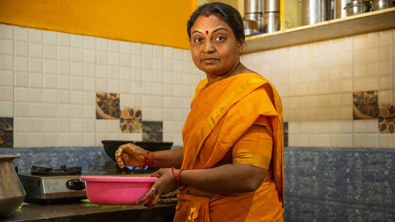 Woman in orange sari preparing food in kitchen